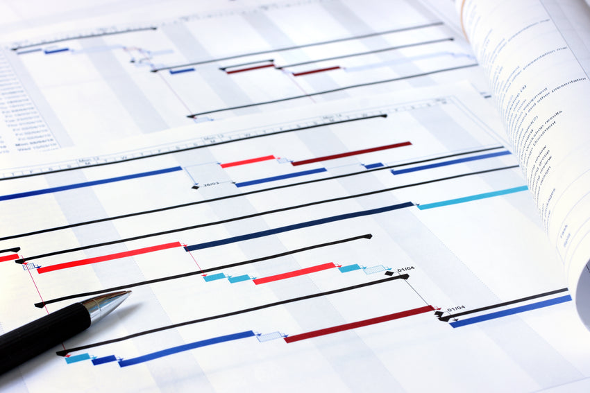 Close up of a label-less Gantt Chart sitting on a desk. It has pens on it to depict in-process project management, as is necessary for LED Digital Display installation.